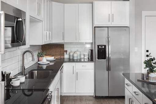 a kitchen with white cabinets and a stainless steel refrigerator
