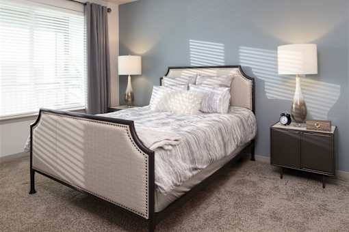 Bedroom with upholstered bed and nightstand lamps at Avli At Crosstown Center Apartments, TAMPA