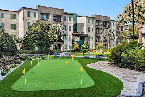 Putting green with seating area and tropical landscaping at Avli At Crosstown Center Apartments, TAMPA, FL