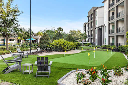 Outdoor putting green with adirondack chairs and courtyard at Avli At Crosstown Center Apartments, TAMPA, 33619