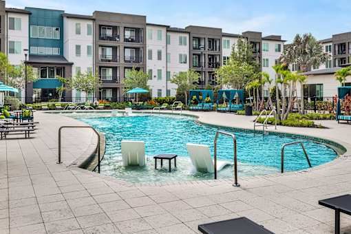 Resort pool with tanning ledge seating and cabanas at Avli At Crosstown Center Apartments, TAMPA, FL
