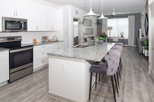 White kitchen with granite island and bar stools at Avli At Crosstown Center Apartments, TAMPA, 33619