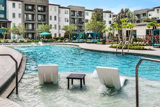 Pool with tanning ledge lounge chairs and table at Avli At Crosstown Center Apartments, TAMPA, Florida