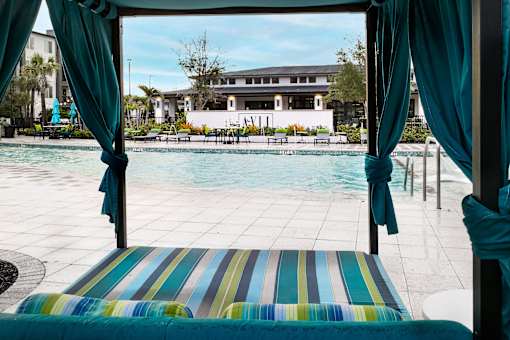 Poolside cabana with striped cushions and teal curtains at Avli At Crosstown Center Apartments, Florida, 33619
