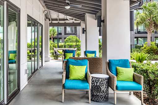 Covered patio with wicker seating and decorative pillows at Avli At Crosstown Center Apartments, TAMPA, Florida
