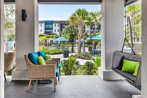Covered patio with wicker seating and poolside views at Avli At Crosstown Center Apartments, TAMPA