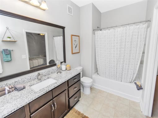 Full bathroom with hard floors, a large counter with wooden cabinetry, and bathtub shower combo