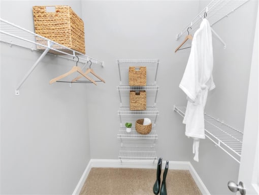 Walk-in closet with 3 long shelves on the side and 5 short stacked shelves in the back with baskets