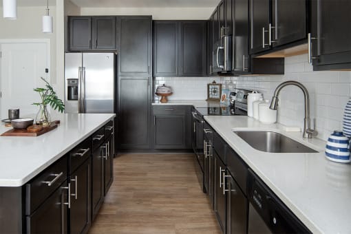 a large kitchen with black cabinets and white countertops and a sink