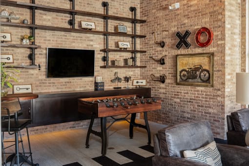 a living room with a brick wall and a game table and a television