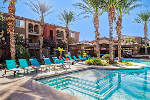 A pool surrounded by palm trees and lounge chairs.