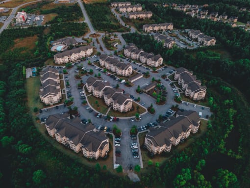Aerial drone view of Riverstone Apartments with outdoor parking surrounded by lush green space