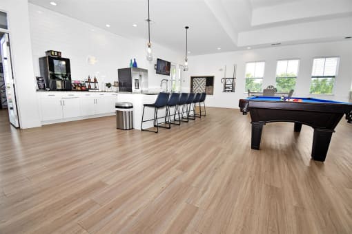 a large living room with hardwood floors and a pool table in the middle of the room