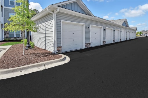 a row of white garage doors in front of a house