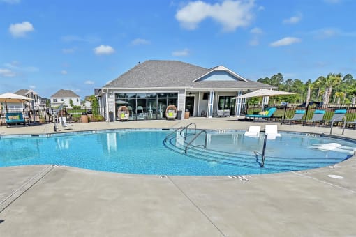 a large pool with lounge chairs and umbrellas in front of a building