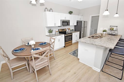 a dining area with a table and chairs and a kitchen in the background