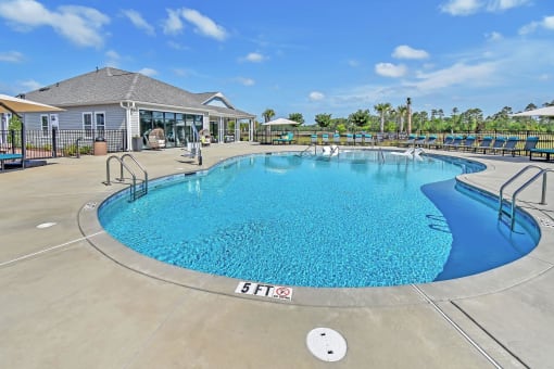 a resort style pool with chaise lounge chairs and a building in the background