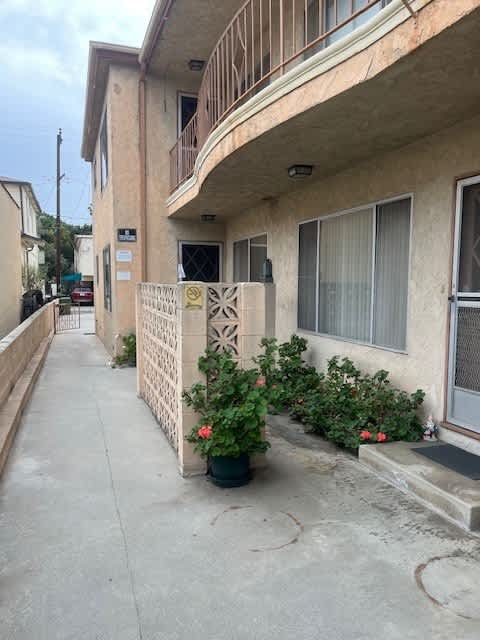 A building with a white fence and a planter with red flowers.