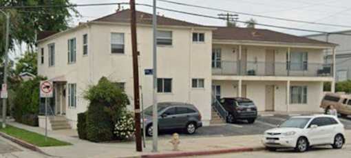 A white car is parked in front of a two-story house.