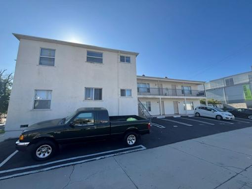 A black pickup truck is parked in a parking lot in front of a white building.