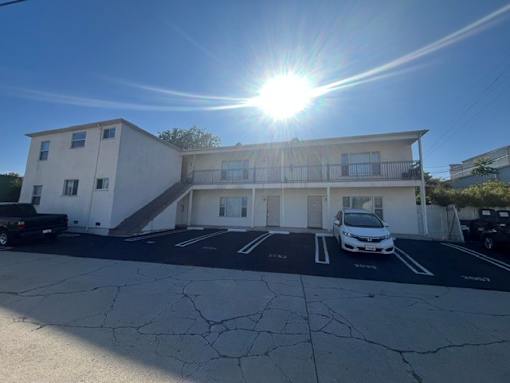 A white building with a car parked in front of it.