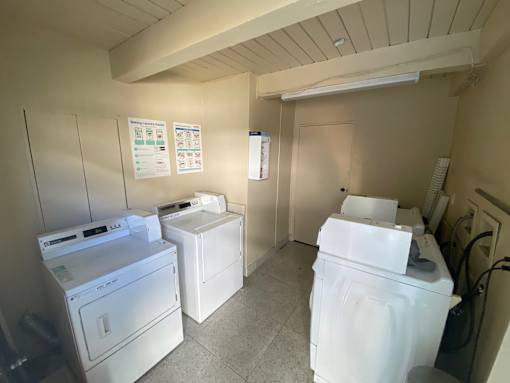 A laundry room with a washer, dryer, and ironing board.