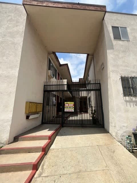 A white building with a black gate and a red staircase.