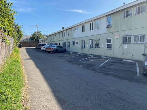 A street view of a residential area with cars parked on the side.