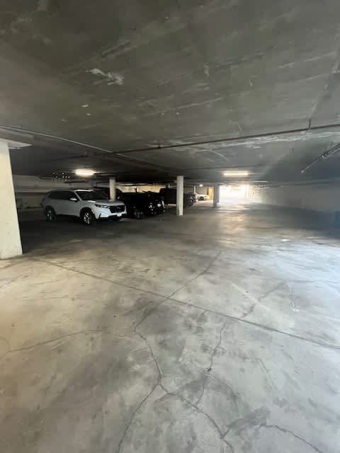 A parking garage with a white car and a black car parked in it.