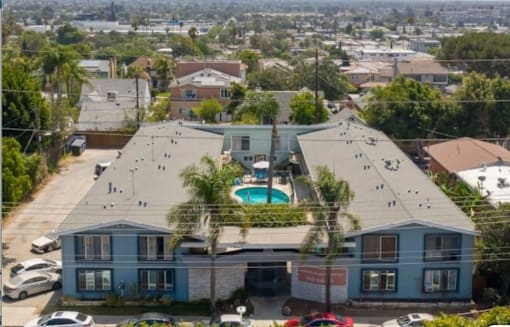 A large blue house with a pool in the middle of a parking lot.