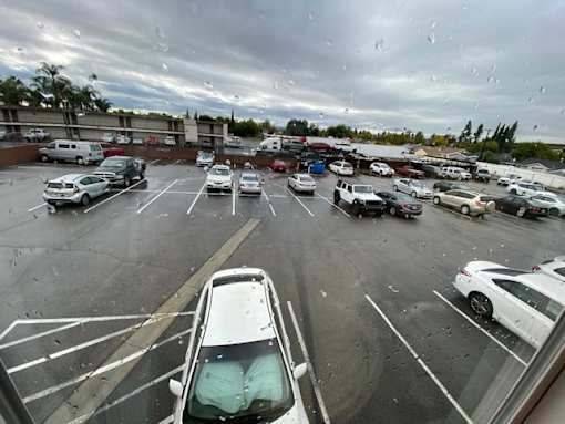 A parking lot with cars and a cloudy sky.