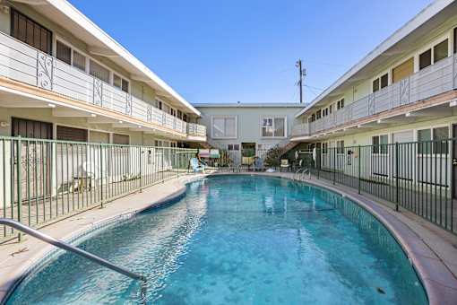 A swimming pool in a residential area surrounded by apartment buildings.