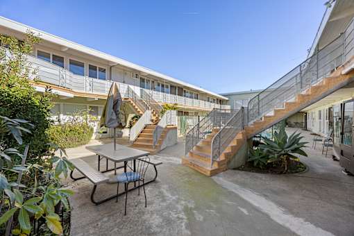 A patio with a table and chairs is surrounded by a building.