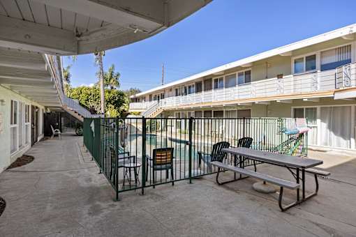 A patio with a table and chairs is surrounded by a fence.