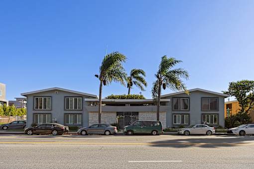 A row of houses with cars parked in front.