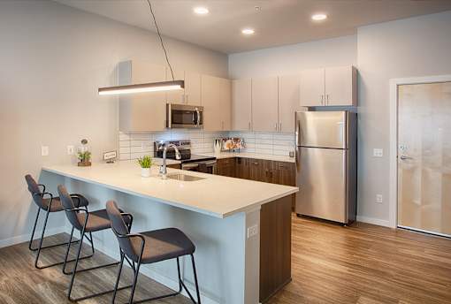 A modern kitchen with a white countertop and stainless steel appliances.