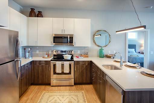 A modern kitchen with a stainless steel refrigerator, wooden cabinets, and a white countertop.