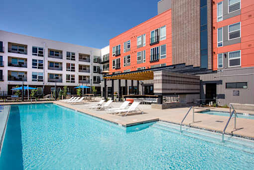 A swimming pool in front of a building with a red and white facade.