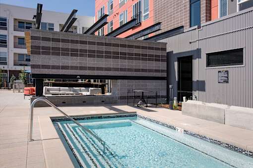 A swimming pool in front of a building with a grey wall.