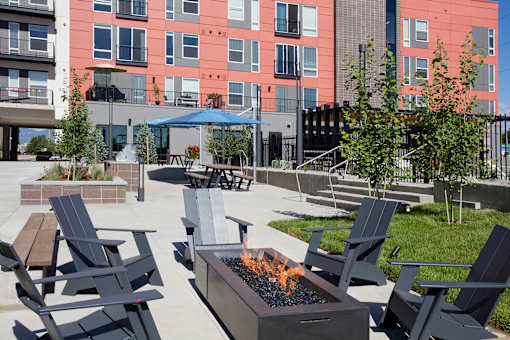 A fire pit sits in the middle of a patio surrounded by chairs.