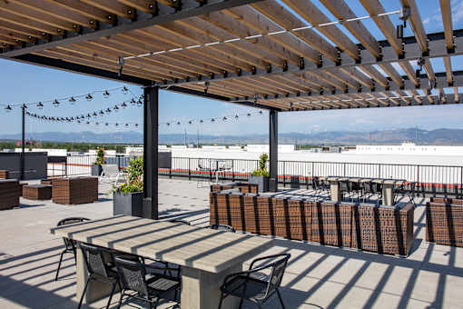 A patio with a table and chairs under a wooden pergola.