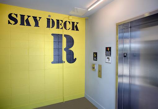 A hallway with a yellow wall and a sign that says Sky Deck.