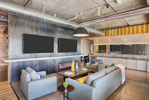 A modern living room with a grey couch and a television mounted on the wall.