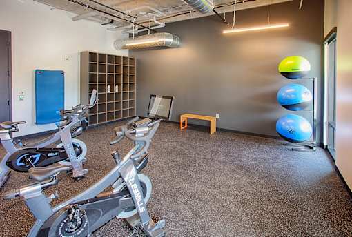 A gym with a row of exercise bikes and a bench.