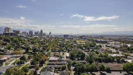 A cityscape with buildings and trees under a blue sky.