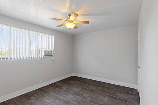 A room with a ceiling fan and a window with blinds.