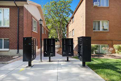 Four black parking meters are lined up on a sidewalk.