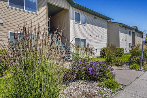 A beige apartment building with a green lawn in front.
