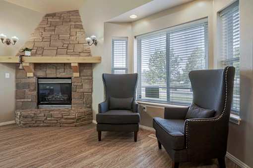 A living room with a stone fireplace and two leather chairs.