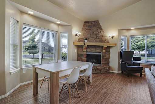 A dining room with a stone fireplace and a table set for four.